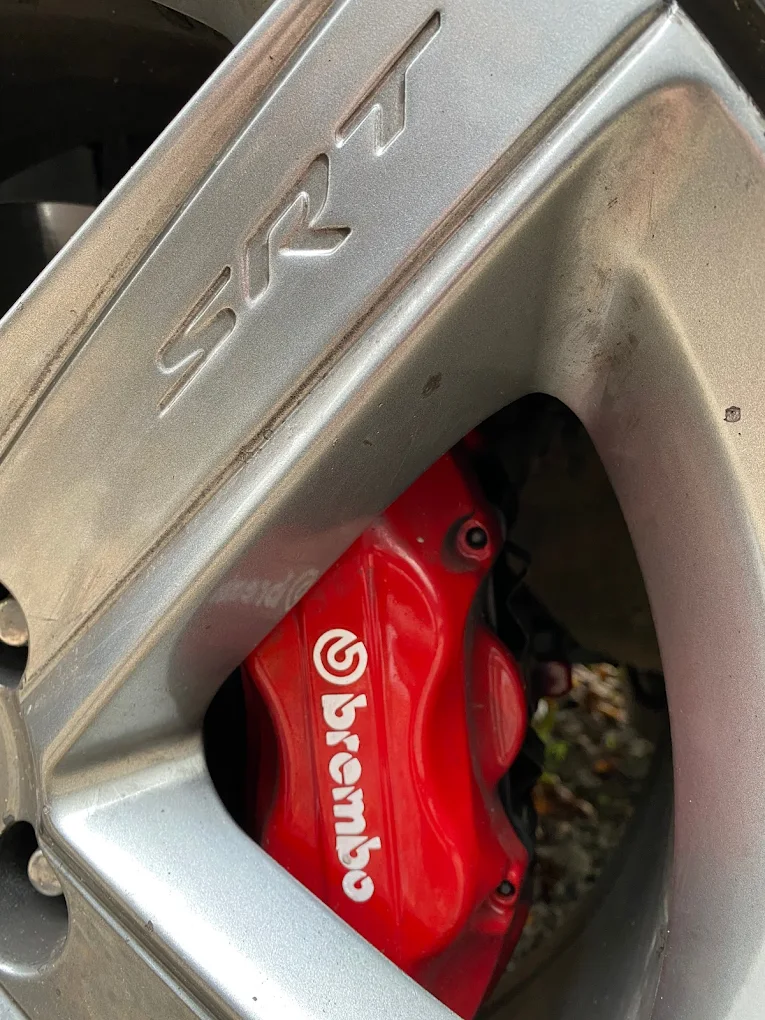 Zacisk hamulcowy Brembo i felga SRT w samochodzie sportowym po serwisie układu hamulcowego.